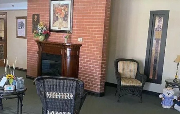 A cozy indoor seating area with a decorative fireplace and wicker chairs.