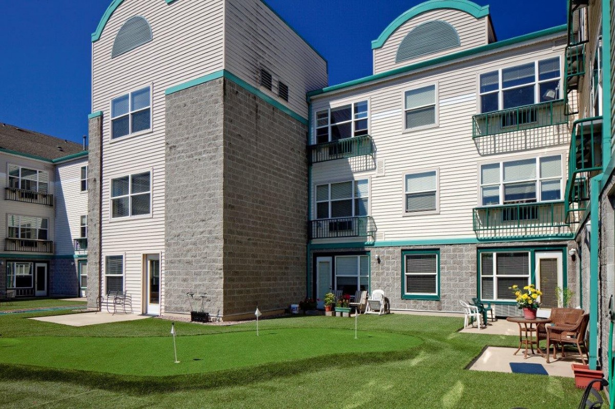A residential apartment building with a well-maintained lawn in the foreground.