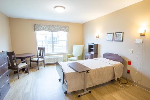 A well-lit and cozy bedroom setup featuring a bed, seating area, and small dining table.