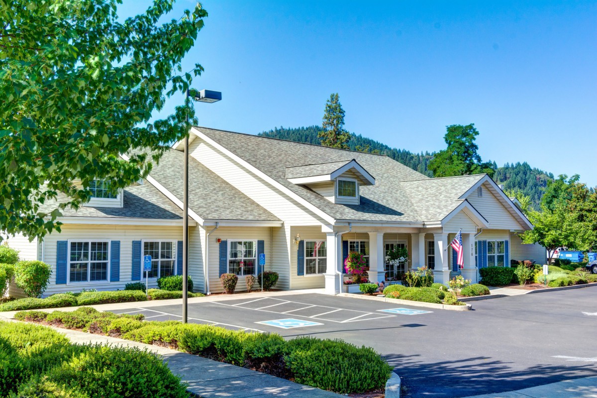 A well-maintained residential building with a landscaped driveway and clear blue skies.
