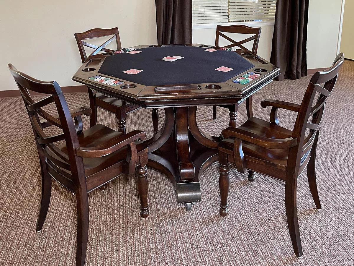 An elegant poker table with four chairs in a game room setting.
