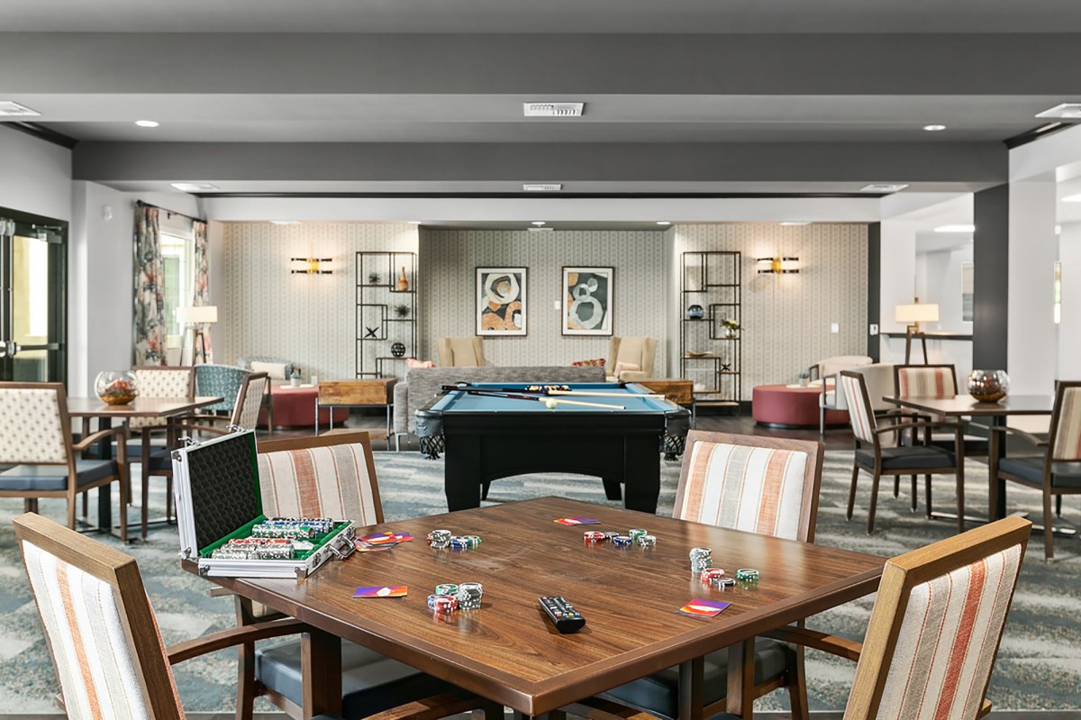 A cozy game room with a pool table and various board games, surrounded by comfortable seating.