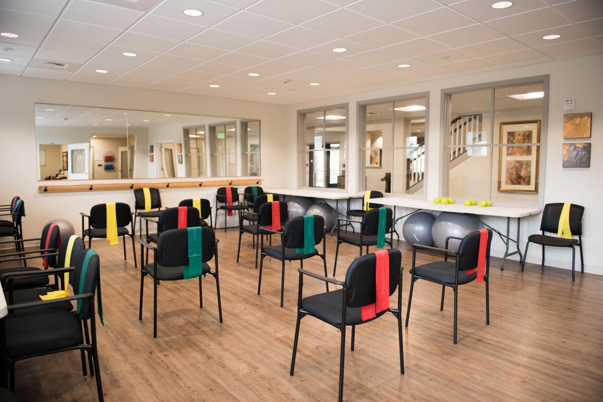 An empty classroom or training room with chairs set up in rows, featuring mirrors on the walls.