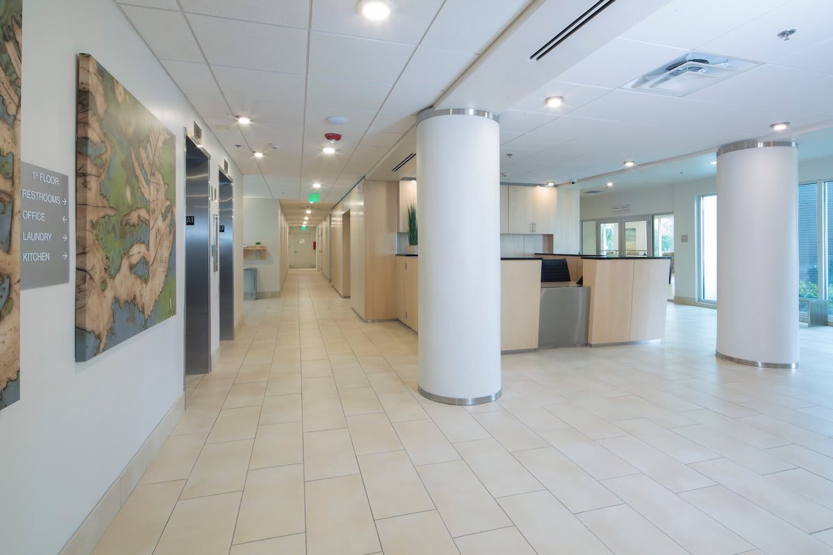 A modern and empty office reception area with a hallway leading to elevators.