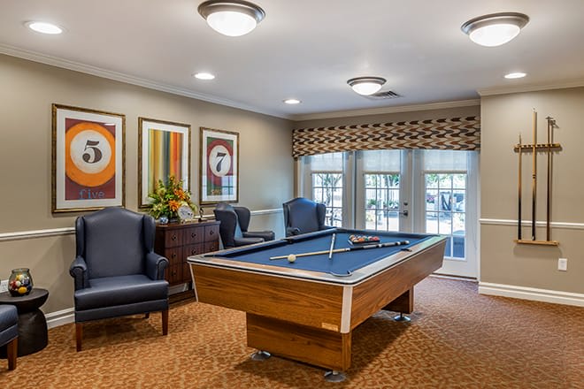 A cozy game room featuring a pool table, artwork, and comfortable seating.