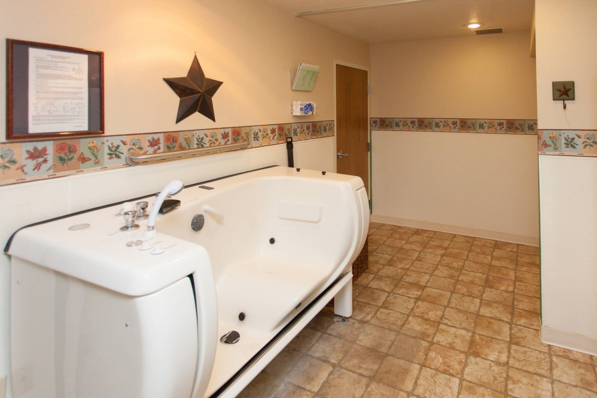 An accessible bathroom featuring a walk-in bathtub and tiled flooring.