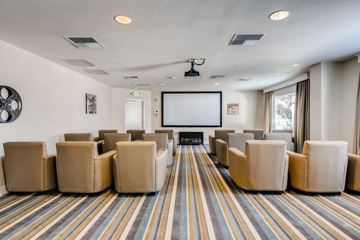 A cozy home theater setup with comfortable seating arranged in front of a large projector screen.