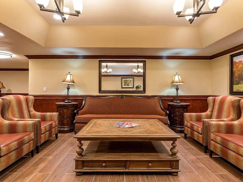 A cozy living room with classic furniture, featuring a central coffee table and warm lighting.