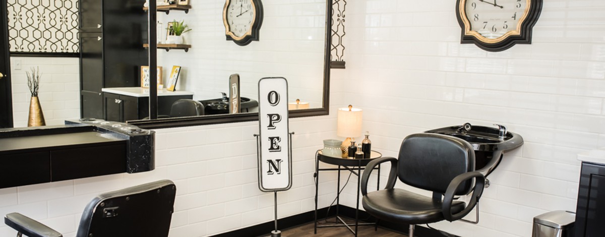 Interior of a salon with an open sign, mirror, and chair.