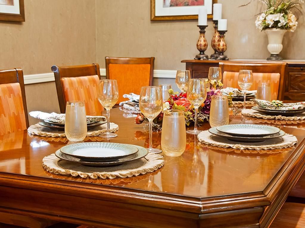 An elegantly set dining table with plates, glasses, and a decorative centerpiece.
