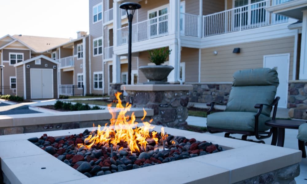 A cozy fire pit in the outdoor area of a modern apartment complex.