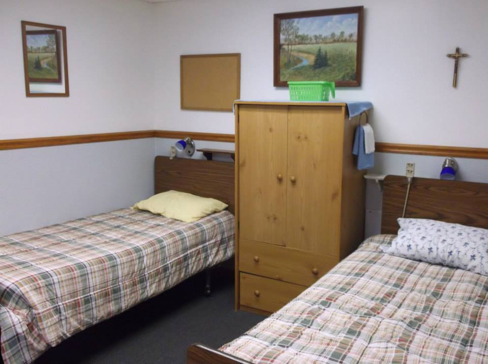 A simple bedroom with two twin beds and wooden furniture.