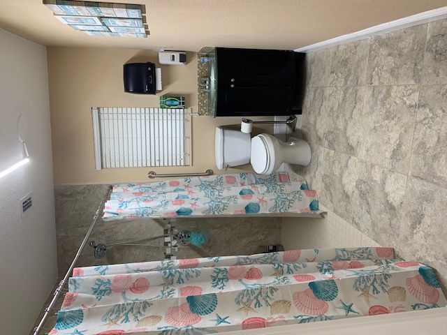 A clean bathroom with a toilet, sink, and floral shower curtain.