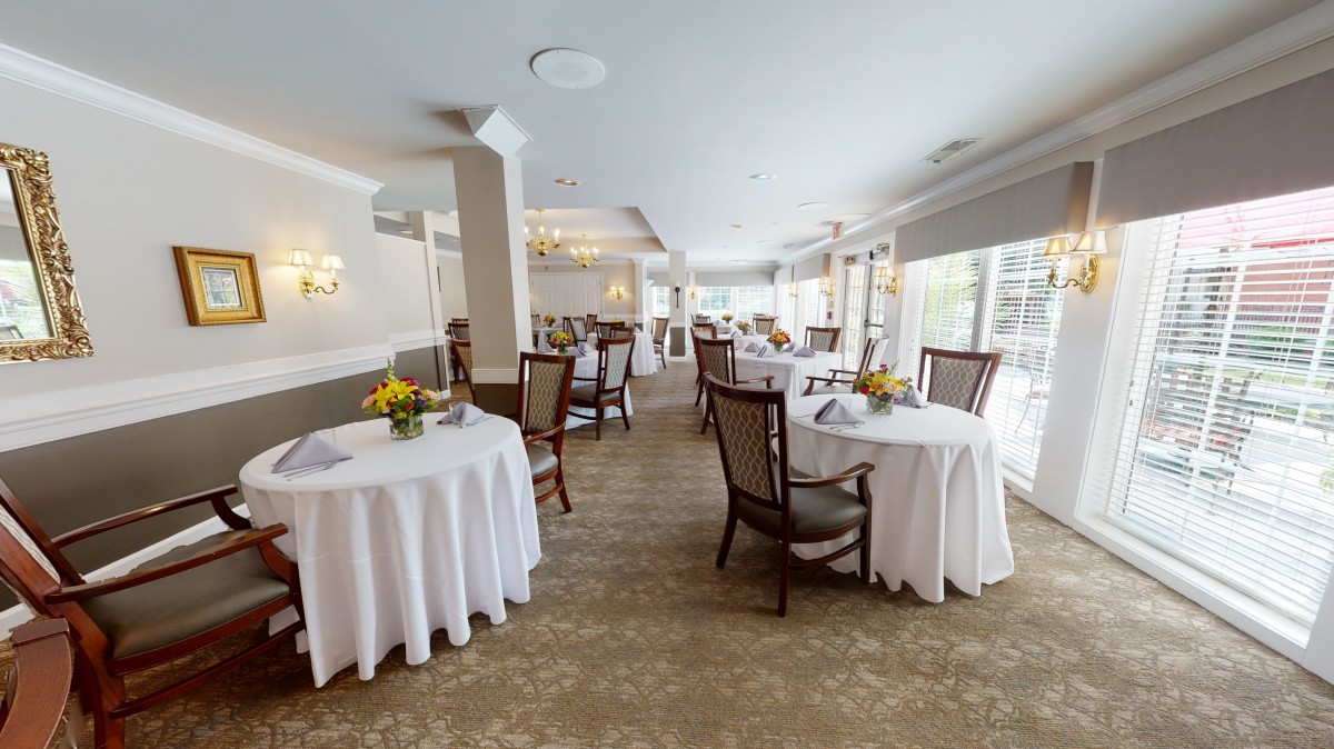 An elegant restaurant dining room with neatly arranged tables covered in white tablecloths.