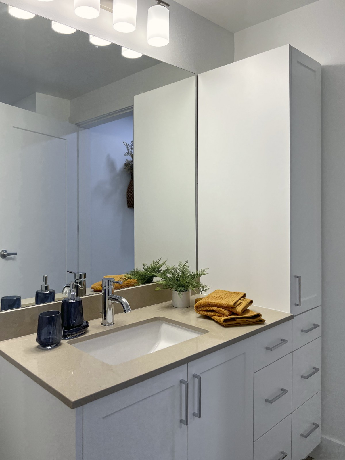 A modern bathroom with a large mirror, sleek countertop, and neatly arranged towels.