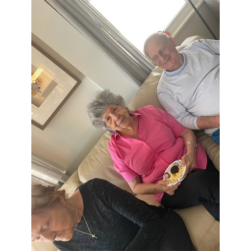 A group of elderly individuals enjoying each other's company while sitting on a couch.