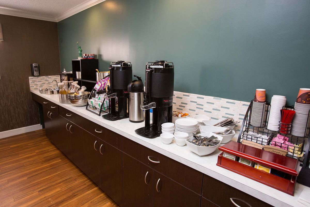 A self-service coffee station with various beverages and supplies on a countertop.
