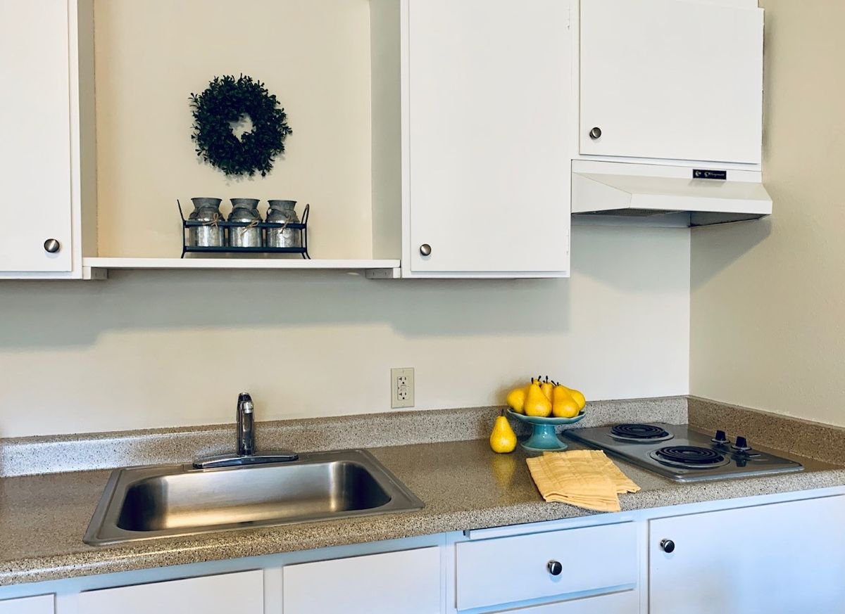 A modern kitchen with white cabinets, a sleek countertop, and decorative elements including lemons in a bowl.