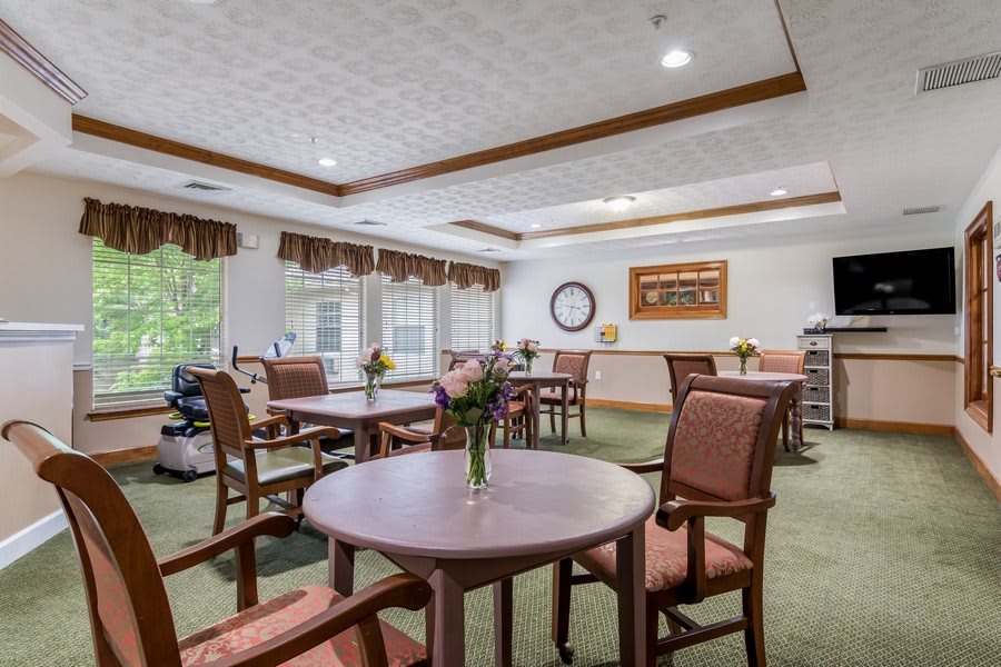 A well-lit dining area with multiple tables and chairs, featuring large windows and tasteful decor.