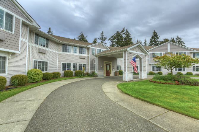 A large building with a circular driveway under a cloudy sky.