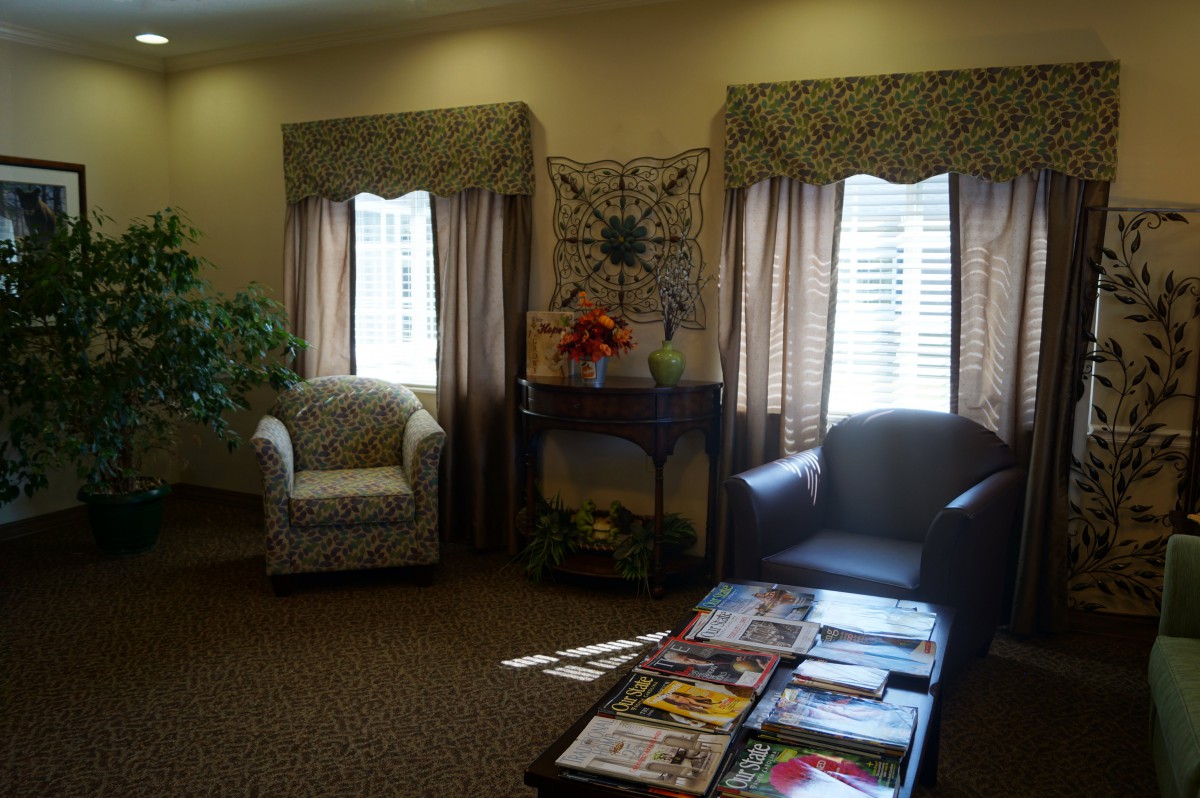 A cozy waiting room with chairs, a coffee table adorned with magazines, and sunlight streaming through the windows.