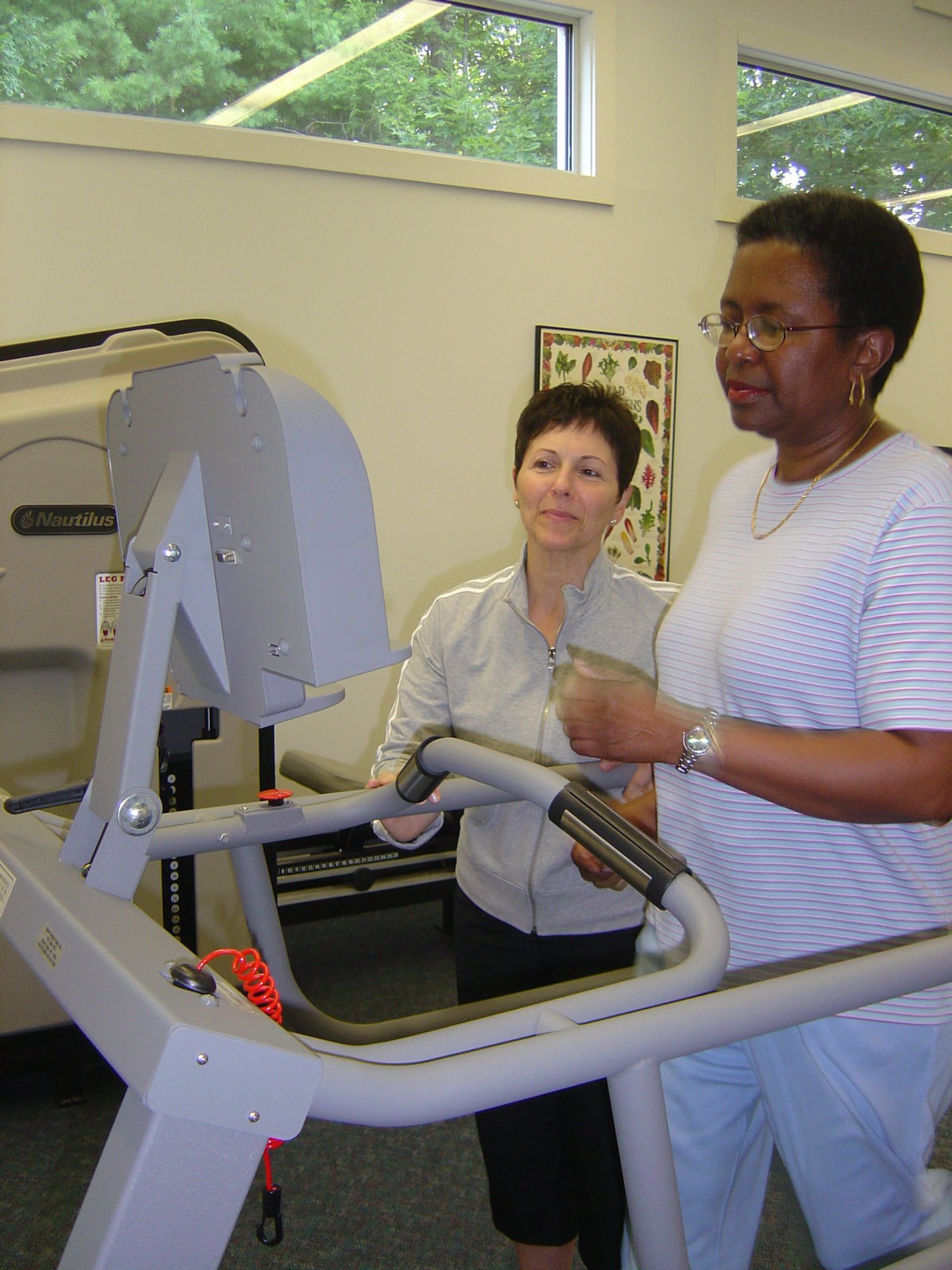 A person receives assistance during a treadmill workout as part of physical therapy.