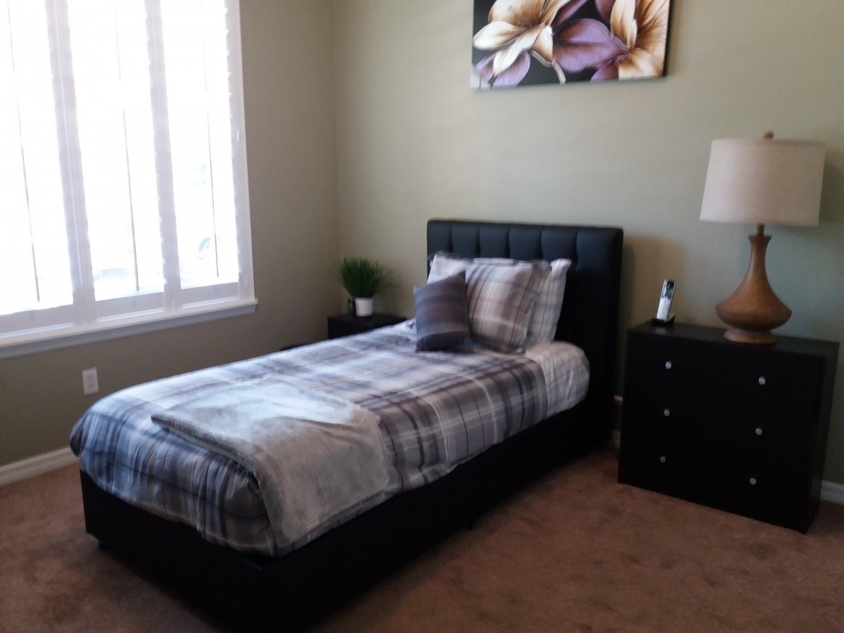 A cozy bedroom with a single bed, nightstand, and a decorative wall painting.