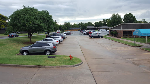 A view of a parking lot with various vehicles parked, set against a cloudy sky.