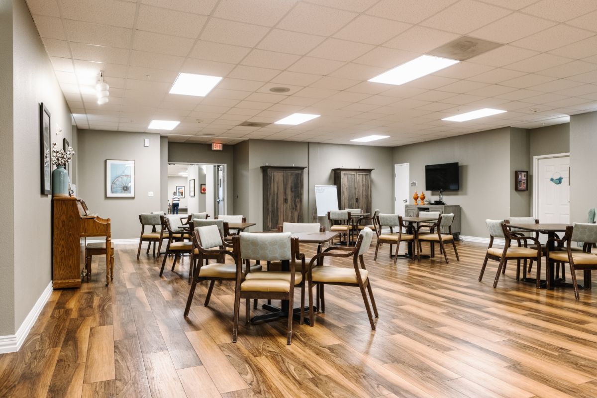 A modern dining area with tables and chairs on a wooden floor.