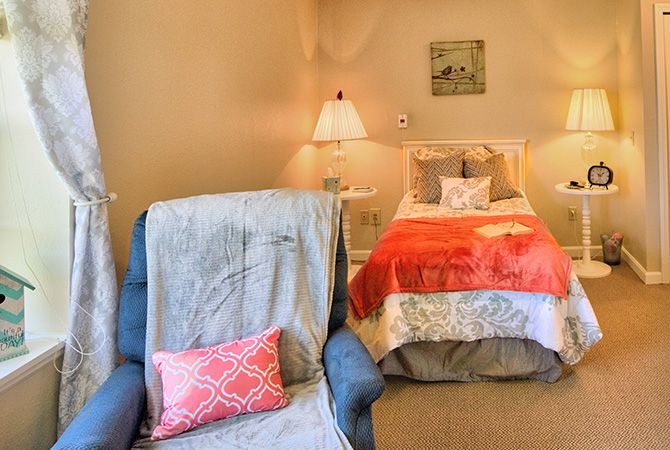 A cozy bedroom setup with a comfy chair and vibrant bedding.