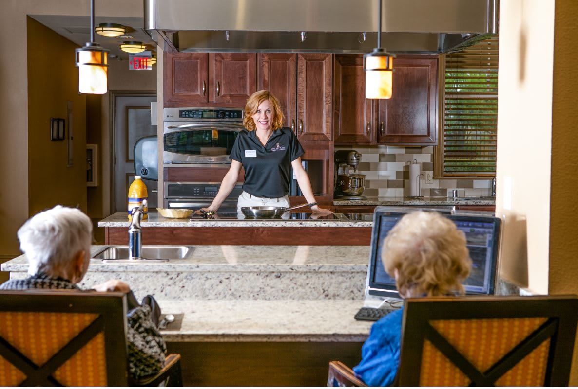 A cooking demonstration in a modern kitchen setting with participants observing.