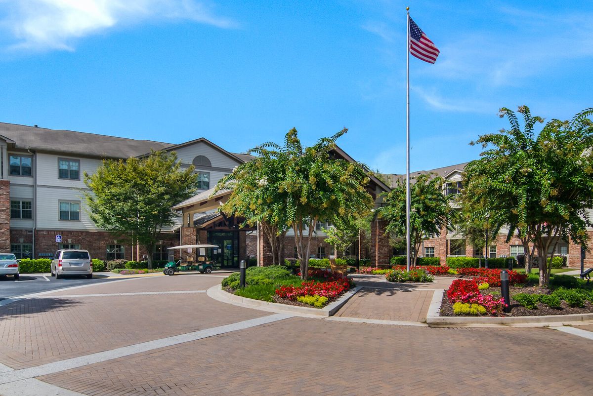 A well-maintained building entrance surrounded by landscaped gardens and an American flag.