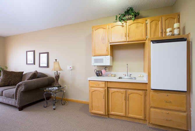 A cozy living space featuring a kitchenette with wooden cabinets and a comfortable couch.