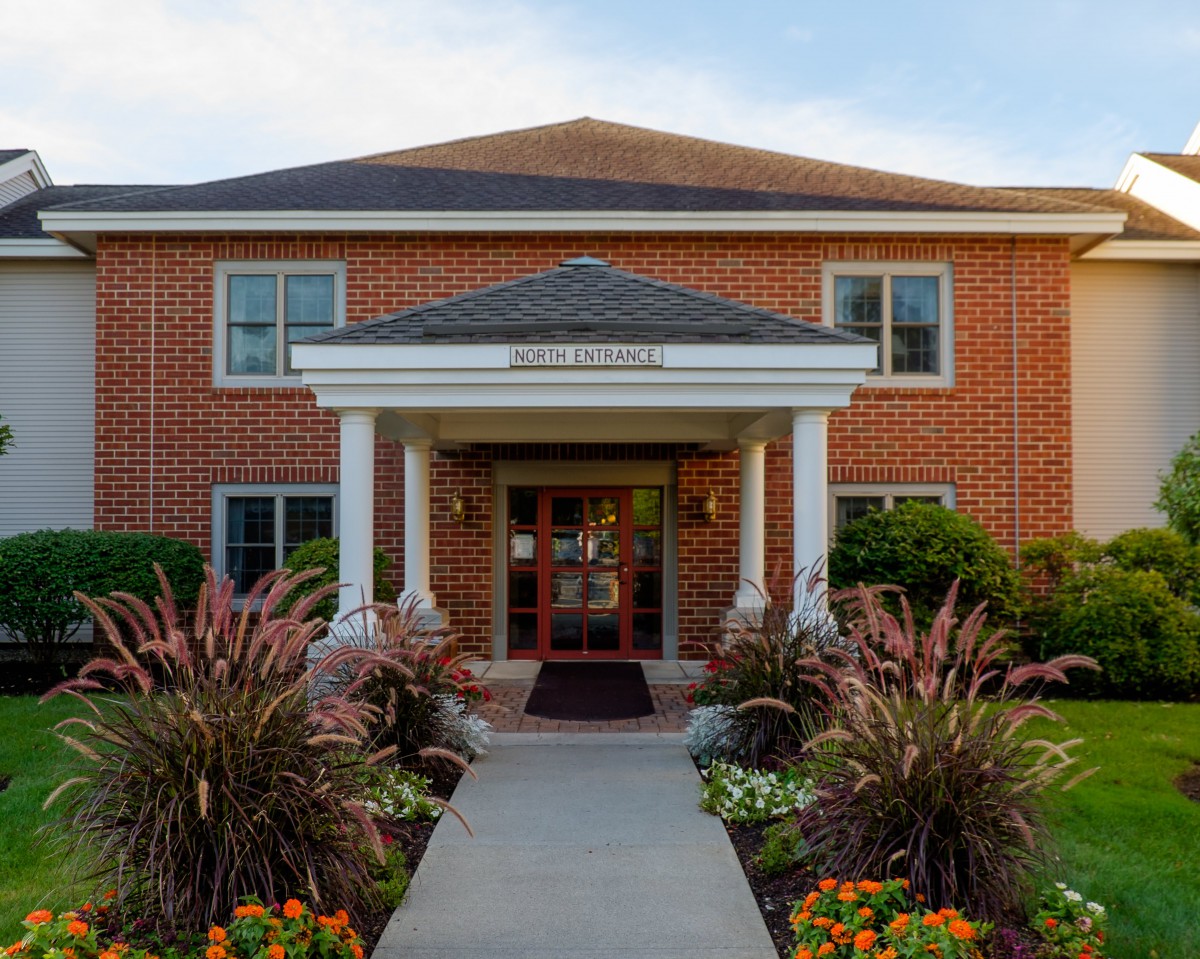 A brick building with a well-landscaped entrance and a pathway leading to the door.
