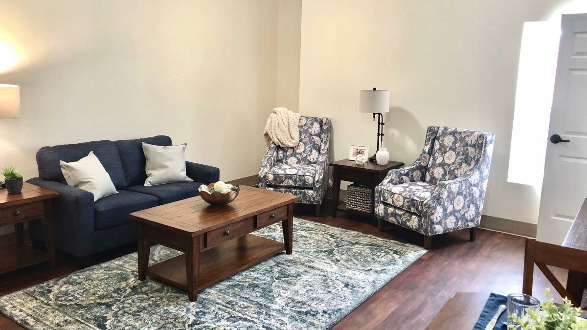 A cozy living room with a navy sofa, patterned armchairs, and a wooden coffee table on a decorative rug.