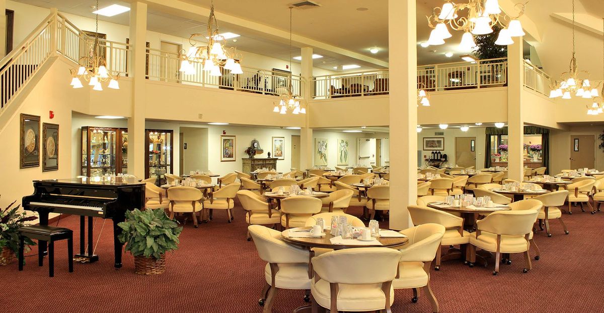 Spacious dining area with multiple tables and chairs, illuminated by chandeliers.