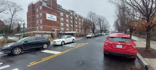 A rainy day view of a residential apartment building with parked cars along the street.