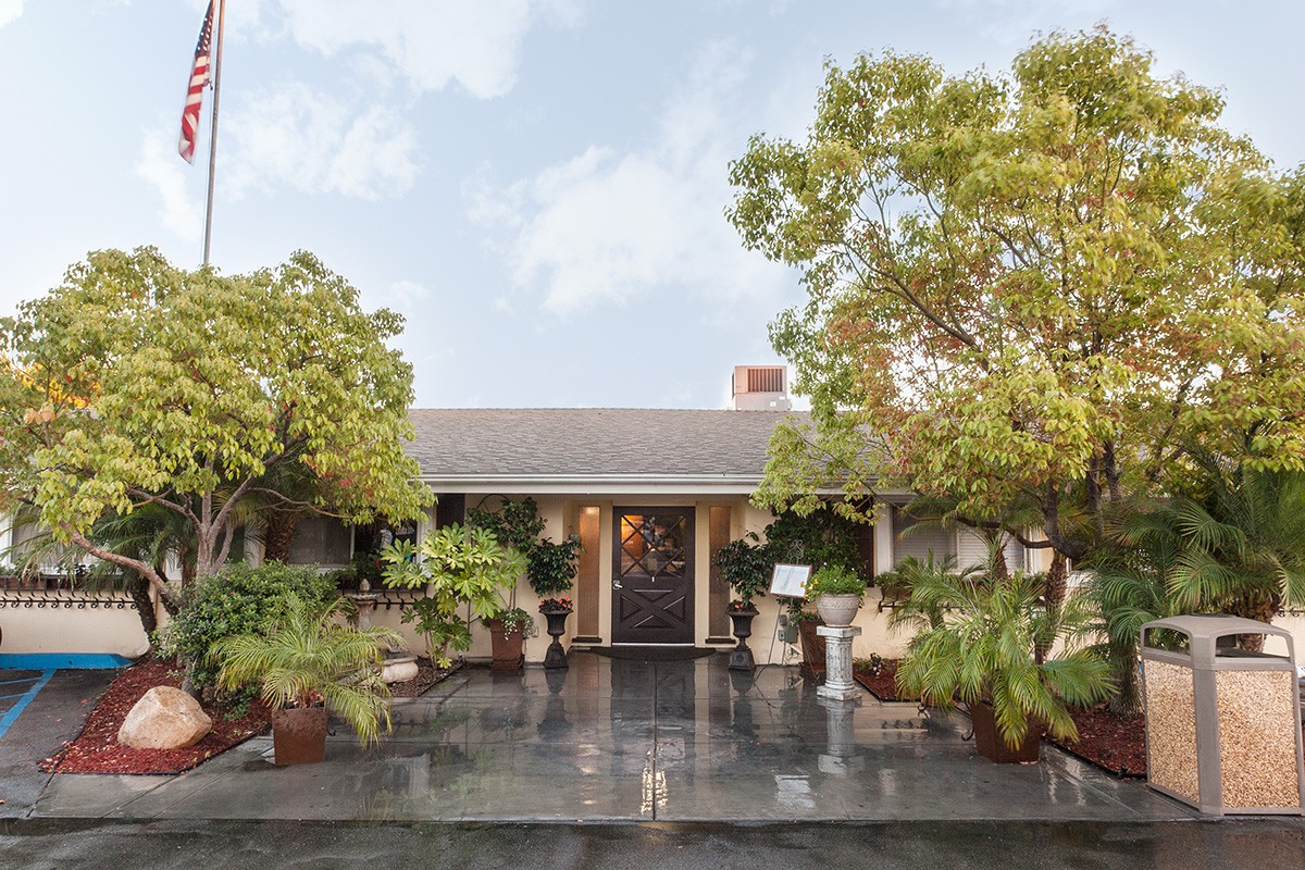 A welcoming house entrance surrounded by lush greenery and potted plants.