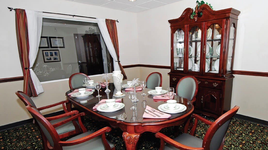 A formal dining room with an elegantly set table and a china cabinet in the background.