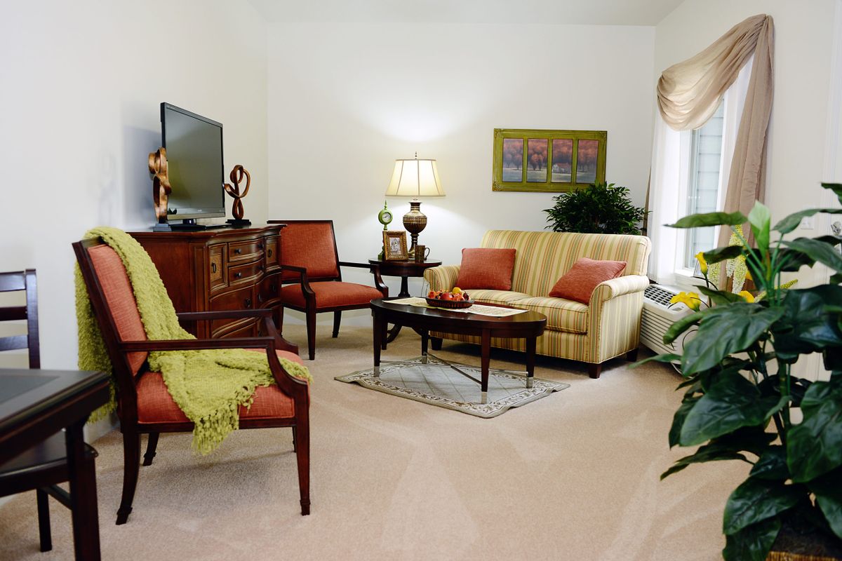 A cozy living room with a sofa, armchairs, and a television.