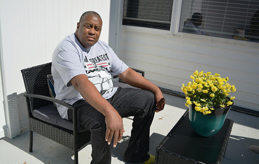 A man relaxing outdoors next to a vibrant flower pot.