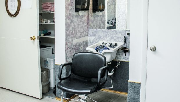 A barbershop interior featuring a chair in front of a wash basin.