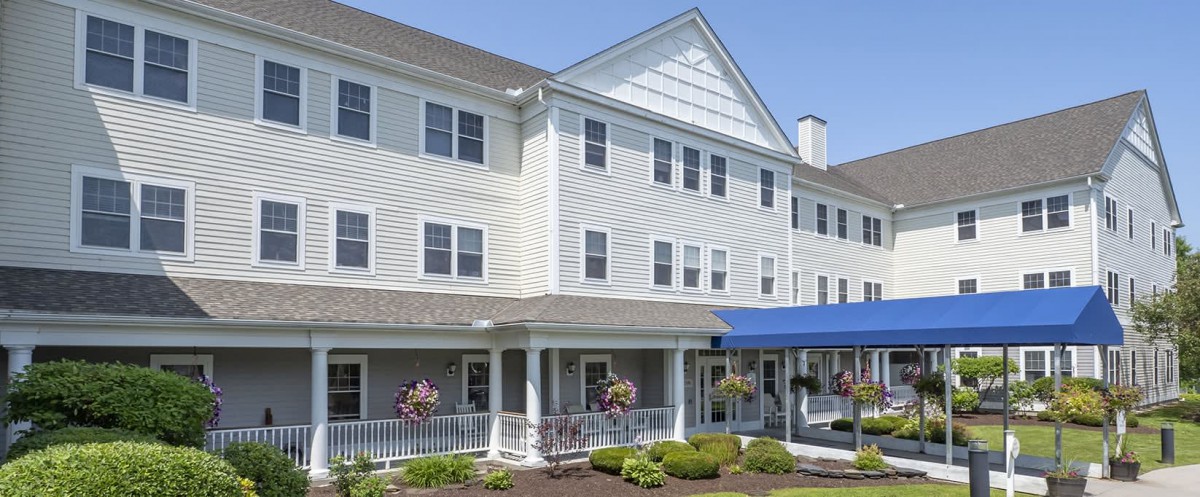 A large, multi-story building with a blue awning and neatly landscaped surroundings.