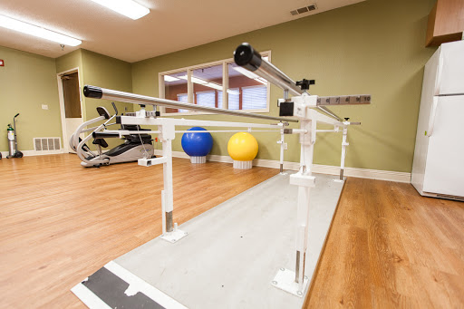 A physical therapy studio equipped with a balance bar and exercise balls.