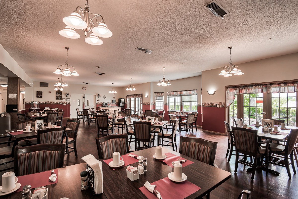 A spacious dining area with neatly arranged tables and chairs, featuring elegant lighting fixtures.