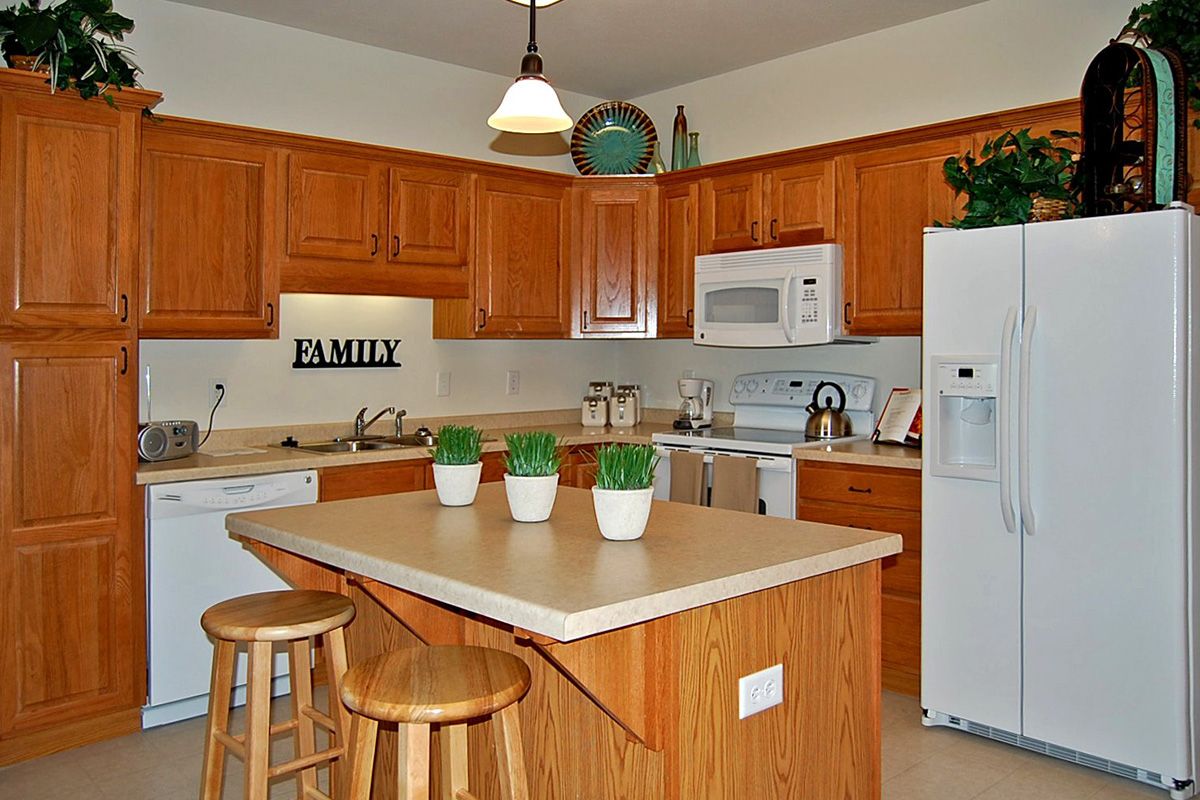 A cozy kitchen with wooden cabinets, a central island, and modern appliances.