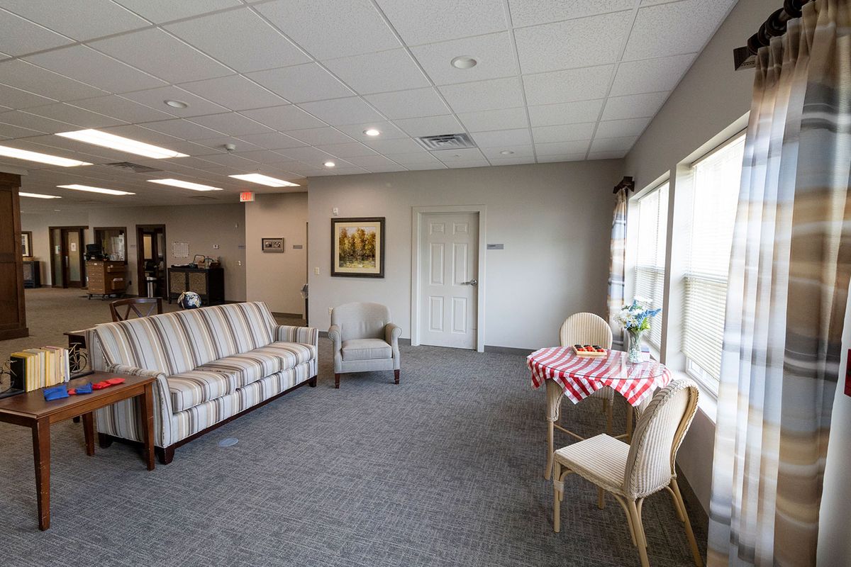 A cozy living room with a sofa, chairs, and a table near large windows letting in natural light.