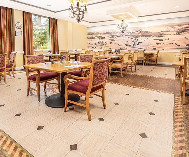 Elegant dining area with neatly arranged tables and chairs, featuring warm lighting and decorative wall art.