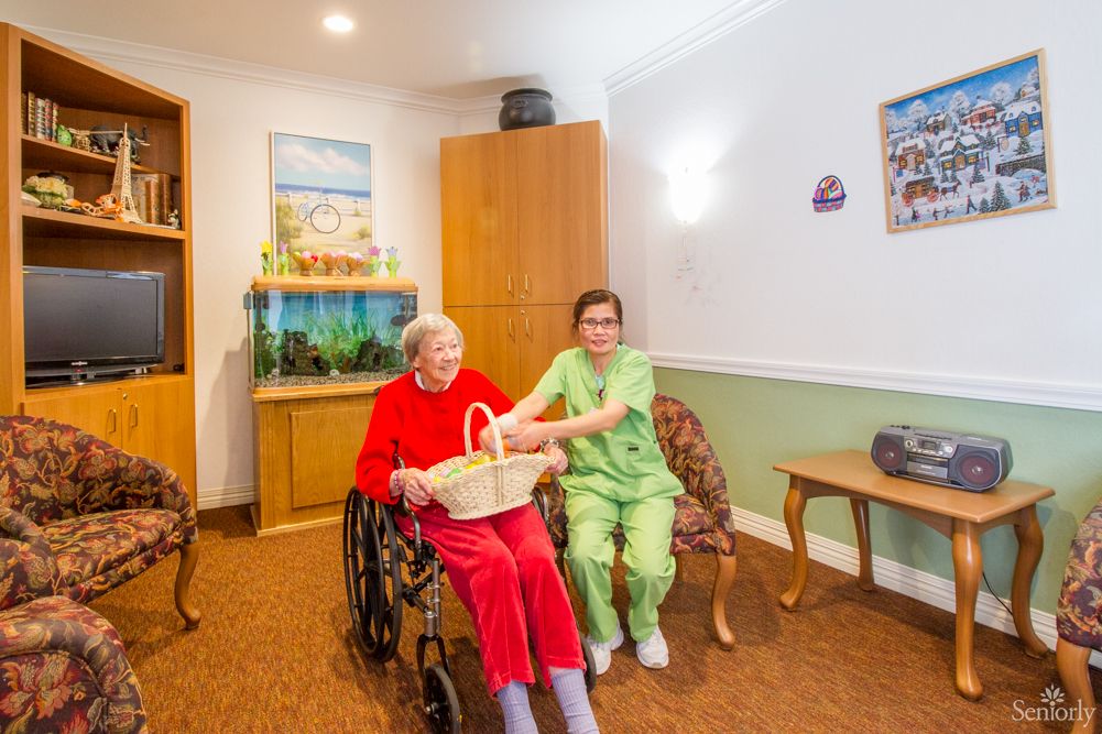 A caregiver assists an elderly person in a wheelchair inside a nursing home.