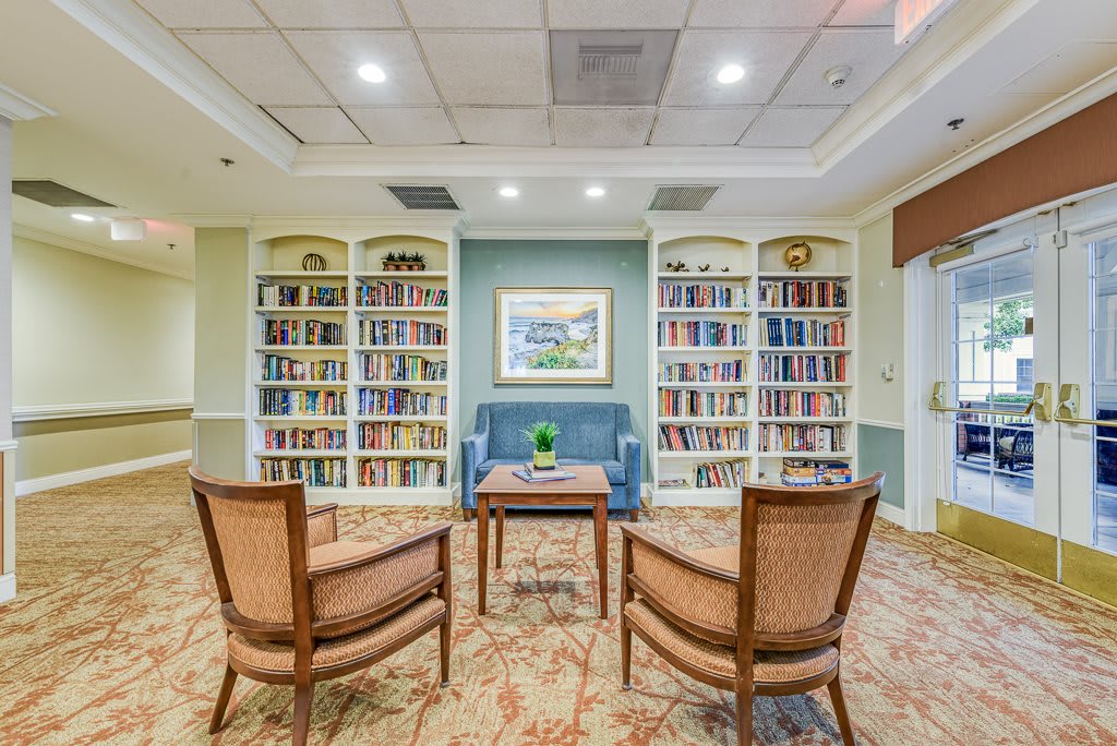A cozy library with bookshelves, a seating area, and a small table.
